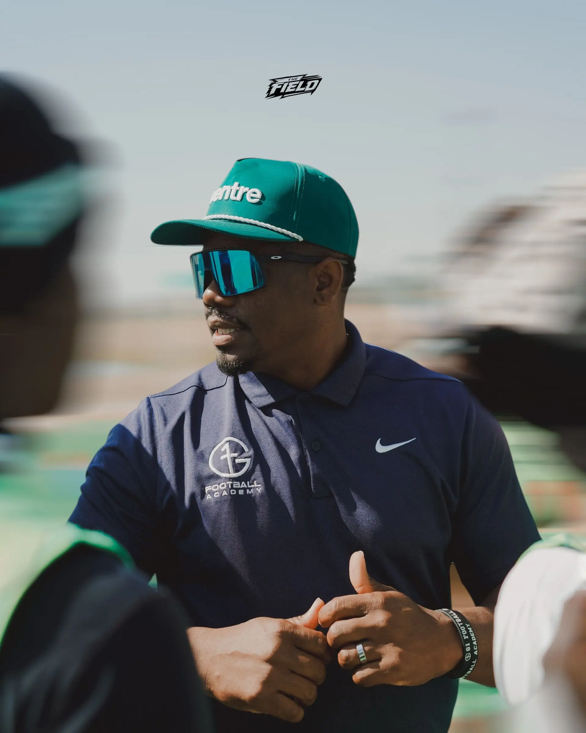 A G1 Football Academy coach on the sideline in a team polo carrying the G1 crest